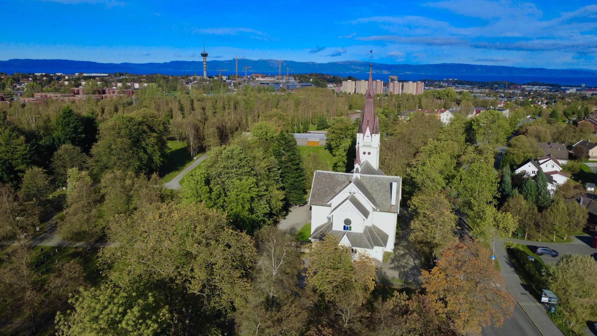 Fargerikt dronefoto av Strinda kirke i Trondheim i skarp høstsol.