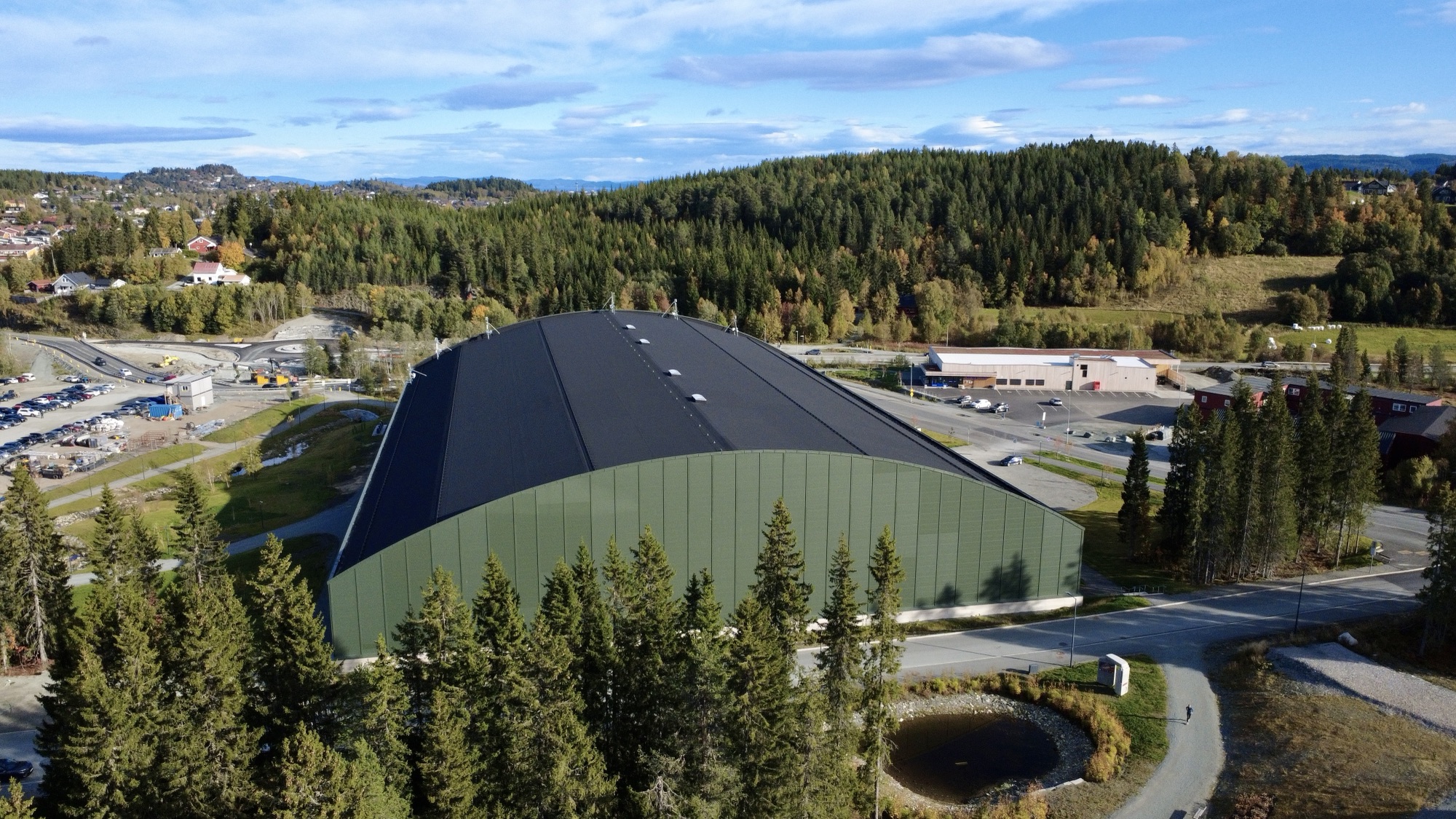 Dronefoto av idrettshall i Granåsen i Trondheim i høstsol
